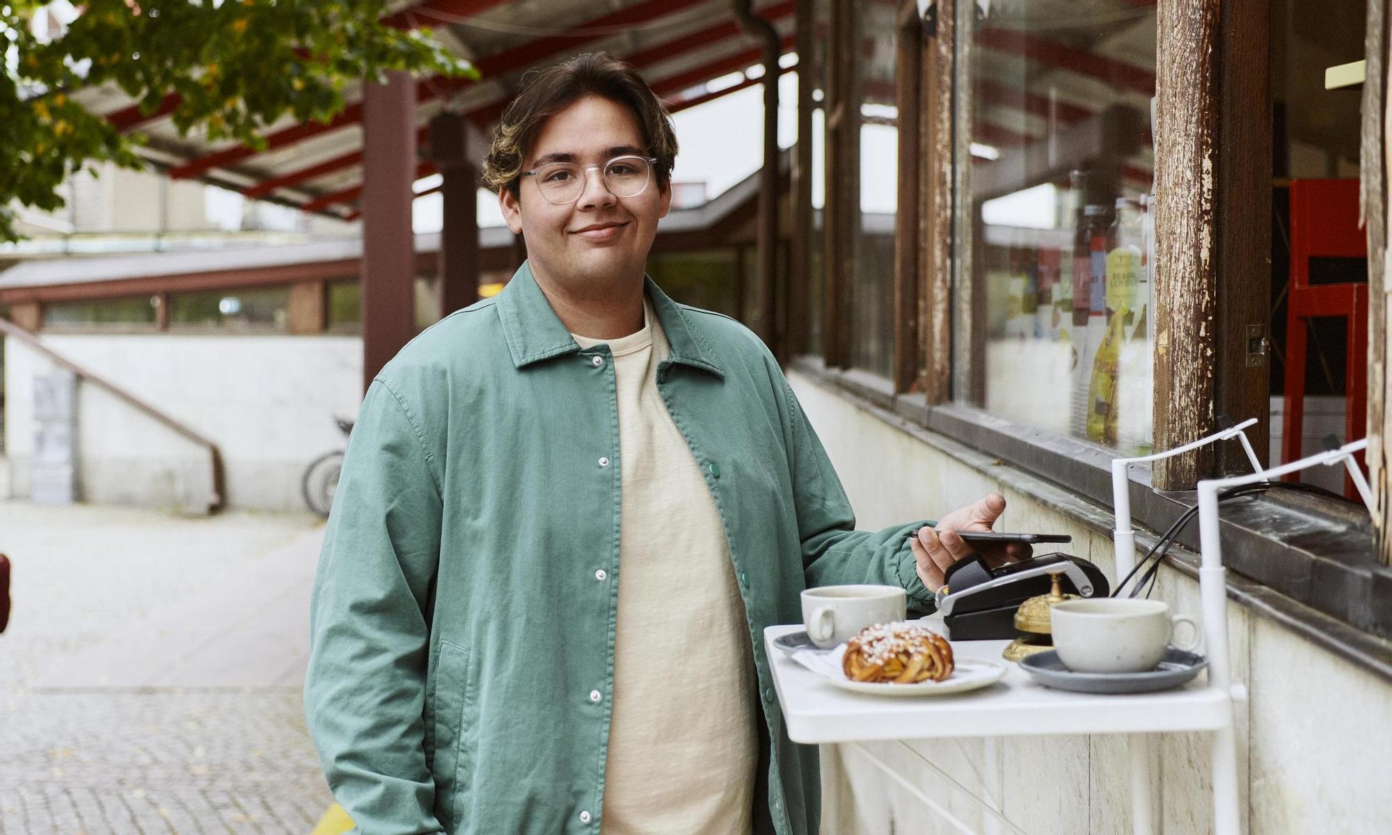 Young man buys coffee with his mobile