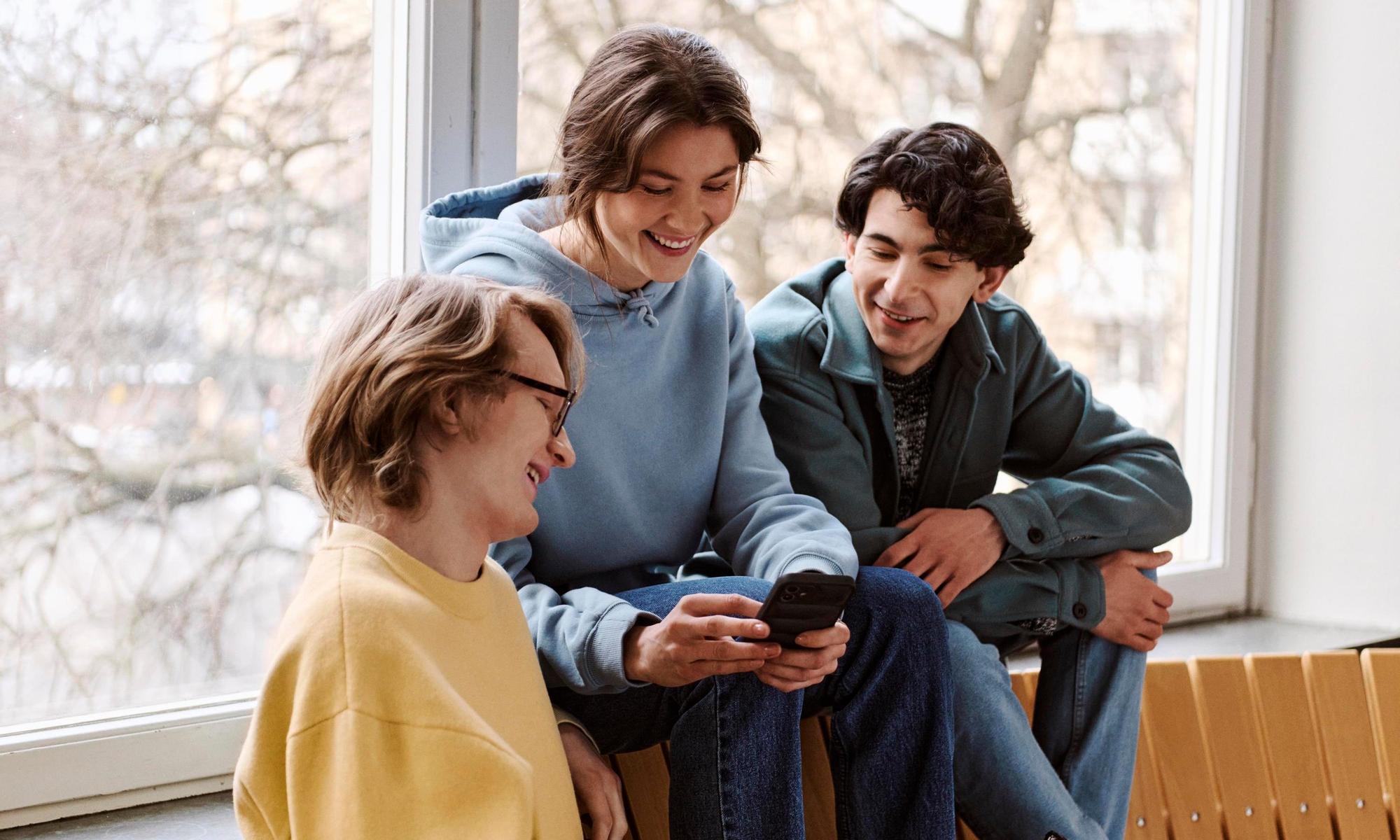 Students on a bench looking at the mobile together