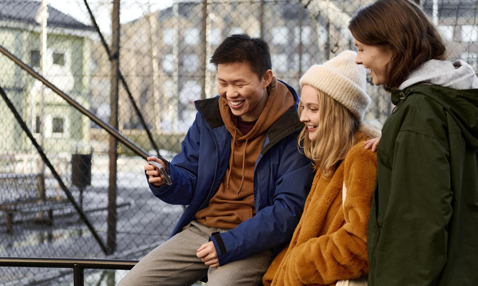 Students hanging outside school looking at a mobile